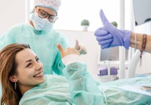 歯科で手術を受ける女性がグッドサインを出している